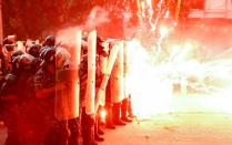 Fireworks are set off in front of police officers during anti-government protests that have been ignited by a massive explosion in Beirut