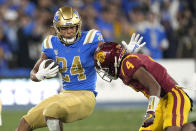 UCLA running back Zach Charbonnet, left, fends off Southern California defensive back Max Williams during the first half of an NCAA college football game Saturday, Nov. 19, 2022, in Pasadena, Calif. (AP Photo/Mark J. Terrill)