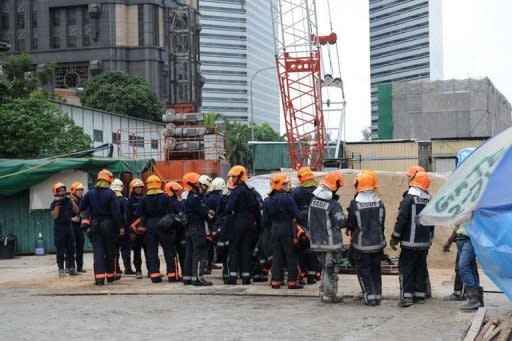 Singaporean rescuers gather outside the Downtown Line (DTL) Bugis Station subway construction site in Singapore on July 18, 2012. Two workers were killed and eight others injured in Singapore when the scaffolding at a subway construction site collapsed on Wednesday, civil defence officials said