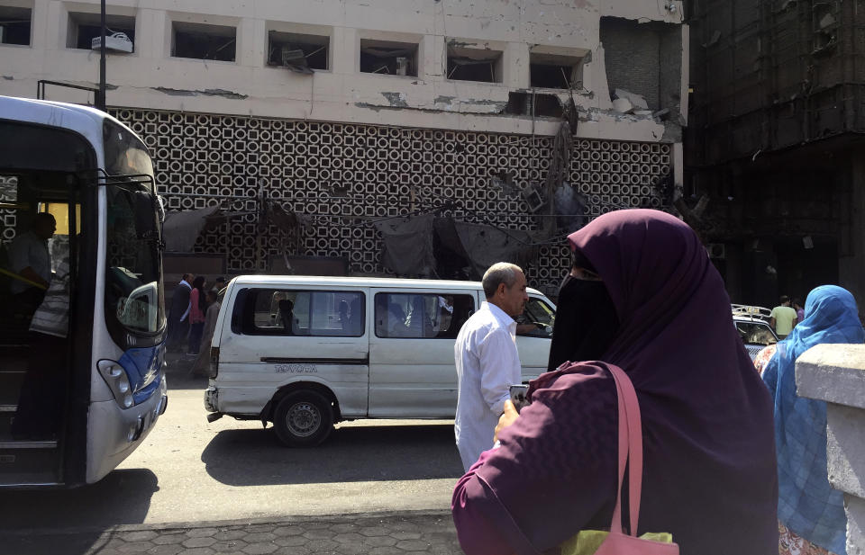 People survey the aftermath of a fiery car crash outside the National Cancer Institute in Cairo, Egypt, Monday, Aug. 5, 2019. The multiple-car crash set off an explosion that ignited a fire at Egypt's main cancer hospital, the government said.(AP Photo/Maya Alleruzzo)