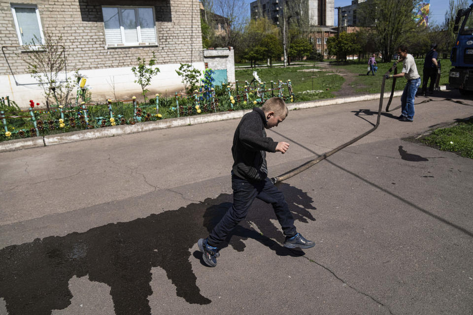 A child jumps over a puddle in Toretsk, eastern Ukraine, Monday, April 25, 2022. Toretsk residents have had no access to water for more than two months because of the war. (AP Photo/Evgeniy Maloletka)