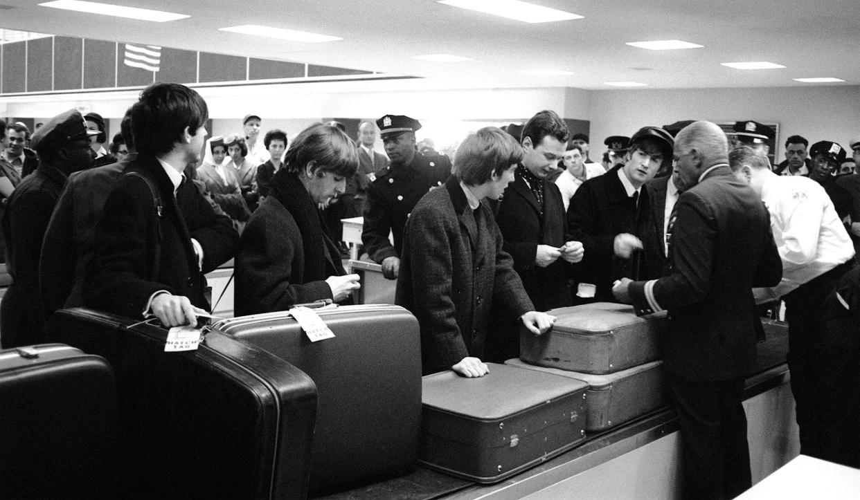 The Beatles and manger Brian Epstein waiting for their luggage after arriving in New York, USA for their first tour of America; left to right: Paul McCartney, Ringo Starr, George Harrison and John Lennon. 7 February 1964. (Photo by Daily Mirror/Mirrorpix via Getty Images)