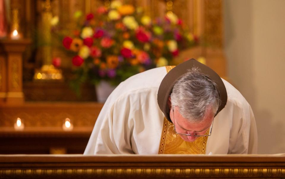 Fr. Michael Weldon kisses the altar at the end of the last Holy Mass he will be celebrating at Saint Mary's Basilica in Phoenix on Saturday, July 1, 2023.