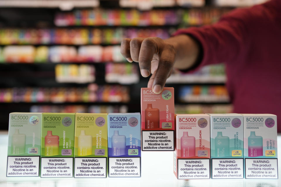 An employee displays some of the varieties of disposable electronic cigarette devices manufactured by EB Design, formerly known as Elf Bar, at Vapes N Smoke in Pinecrest, Fla., Monday, June 26, 2023. Since 2020, the number of different e-cigarette devices for sale in the U.S. has exploded to more than 9,000, a nearly three-fold increase driven almost entirely by a wave of disposable vapes from China. (AP Photo/Rebecca Blackwell)