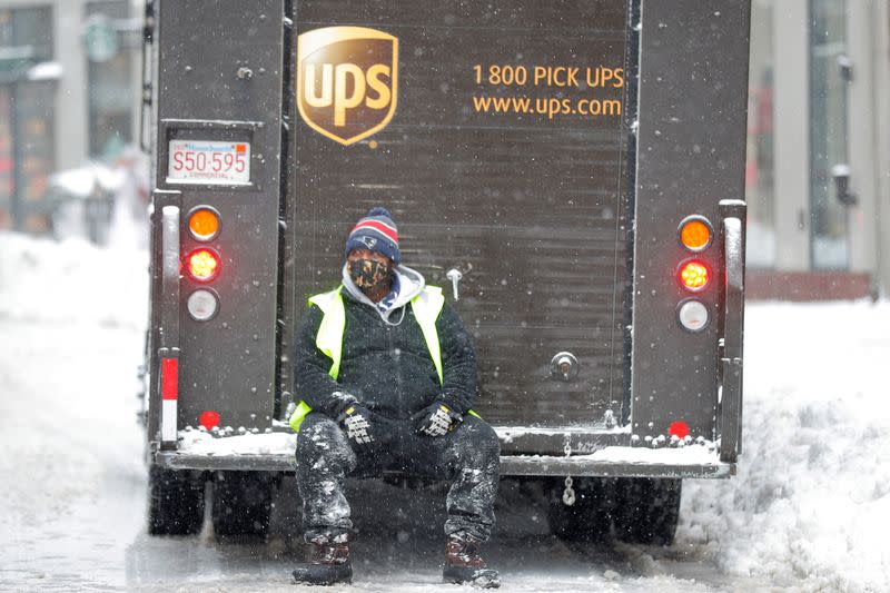 A worker sits on the back of a UPS delivery truck during a snow storm in Boston