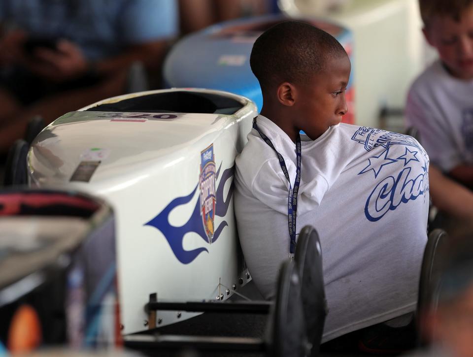 Shelton Taylor, 10, of Indianapolis, Ind., rests by his derby car Saturday.