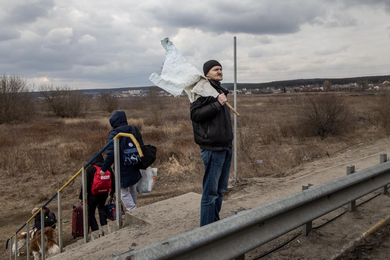 A resident holds a white flag as he flees heavy fighting via a destroyed bridge as Russian forces entered the city on March 07, 2022, in Irpin, Ukraine.