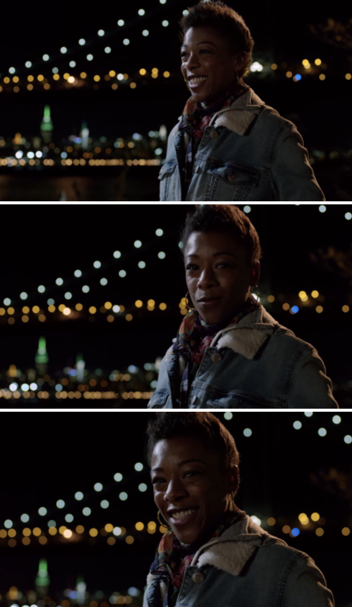 Poussey standing with the city skyline behind her at night, smiling