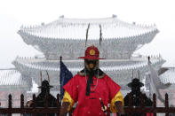 An Imperial guard wearing a face mask stands in the snow outside the Gyeongbok Palace, the main royal palace during the Joseon Dynasty in Seoul, South Korea, Monday, Feb. 17, 2020. Chinese authorities on Monday reported a slight upturn in new virus cases and hundred more deaths for a total of thousands since the outbreak began two months ago. (AP Photo/Ahn Young-joon)