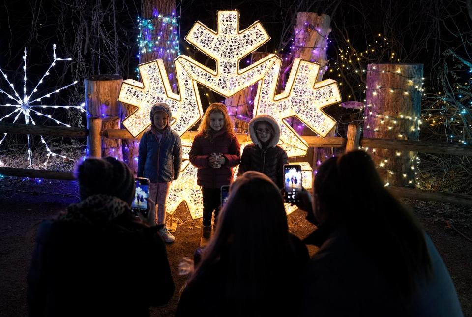 Visitors from neighboring Massachusetts stop by a giant snowflake to take photos during a visit to the Roger Williams Park Zoo Holiday Lights Spectacular in November 2022.