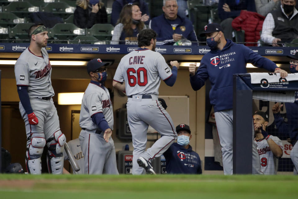 Minnesota Twins' Jake Cave (60) is congratulated in the dugout after scoring from third base on a wild pitch during the third inning of an opening day baseball game against the Milwaukee Brewers on Thursday, April 1, 2021, in Milwaukee. (AP Photo/Aaron Gash)