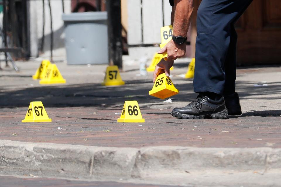 Authorities remove evidence markers at the scene of a mass shooting, Sunday, Aug. 4, 2019, in Dayton, Ohio.