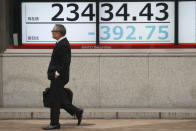 A man walks by an electronic stock board at a securities firm in Tokyo, Monday, Jan. 27, 2020. Shares tumbled Monday in the few Asian markets open as China announced sharp increases in the number of people affected in an outbreak of a potentially deadly virus. (AP Photo/Koji Sasahara)