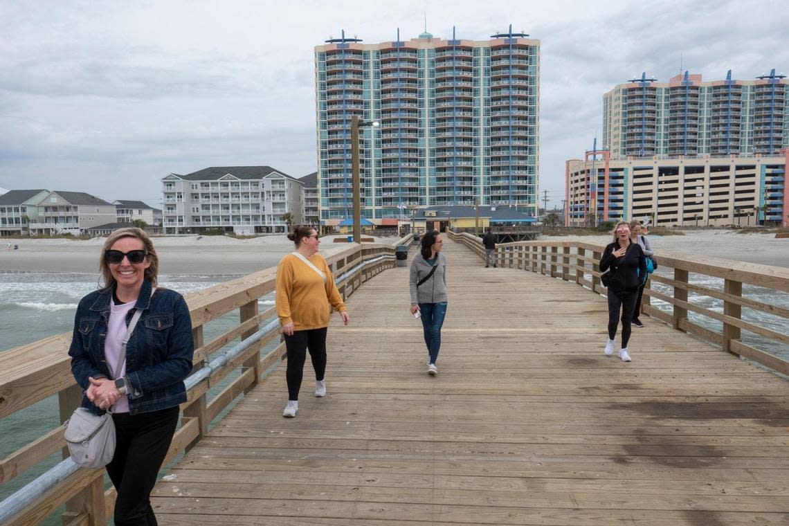 Canadian tourists walk a newly completed section of the Cherry Grove Pier on Friday. March 22, 2024.