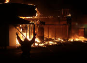 <p>A person poses for a photo for his friend in front of a burning Title Max Loans business along West Florissant Avenue in Ferguson, Missouri on November 25, 2014. Protesters took to the streets, erupting in mass looting and confrontation with riot police throughout the night, after a grand jury did not indict Ferguson Police Officer Darren Wilson in the shooting death of unarmed teenager Michael Brown. (Laurie Skrivan/TNS/ZUMA Wire) </p>