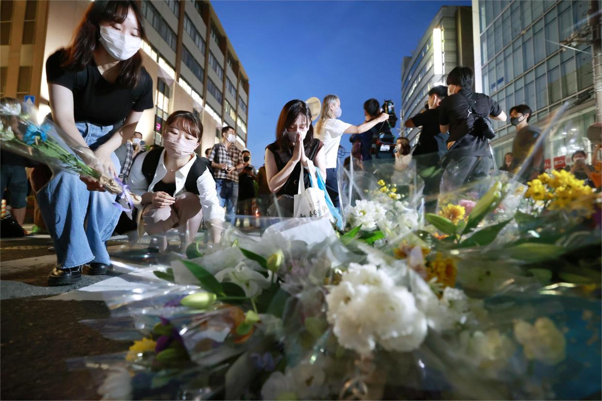 People pray at a makeshift memorial at the scene where former Prime Minister Shinzo Abe was shot while delivering a speech to support the Liberal Democratic Party's candidate during an election campaign in Nara. 