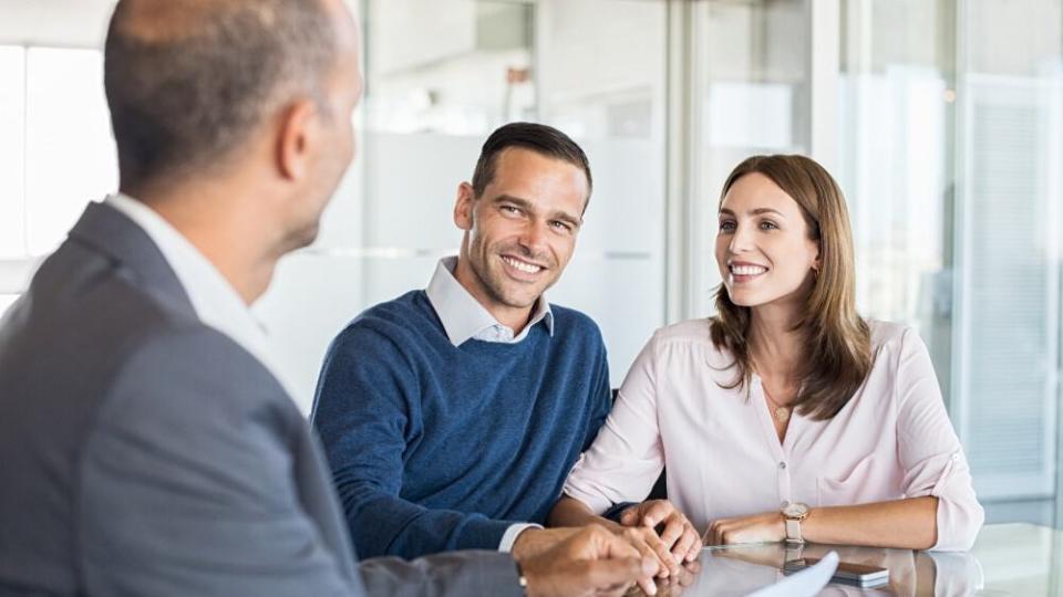 Mature financial advisor showing report to young couple for their investment