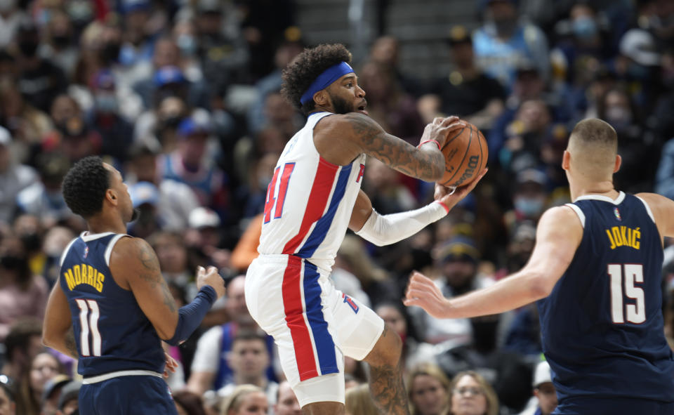 Detroit Pistons forward Saddiq Bey, center, drives to the basket between Denver Nuggets guard Monte Morris, left, and center Nikola Jokic in the second half of an NBA basketball game Sunday, Jan. 23, 2022, in Denver. (AP Photo/David Zalubowski)