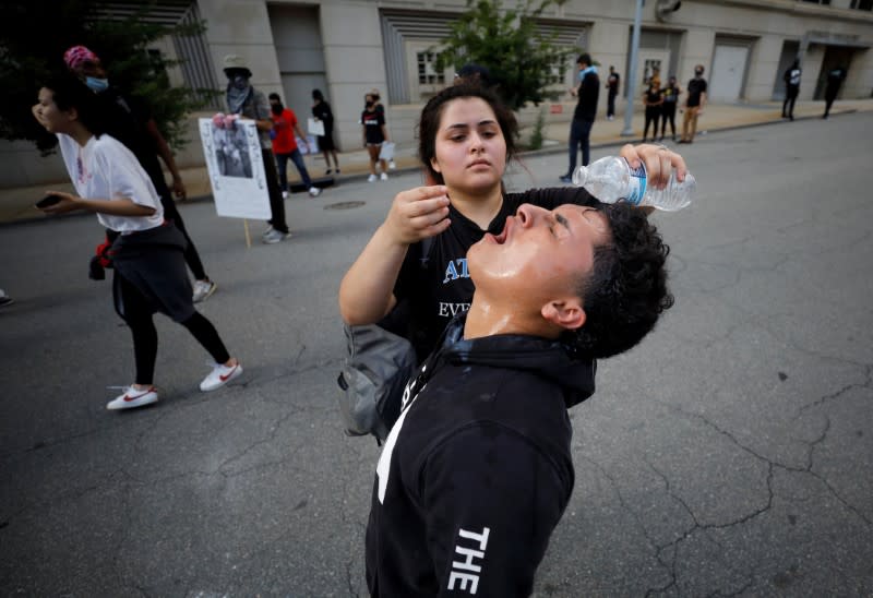 Manifestante vierte agua en los ojos de un amigo afectado por el gas lacrimógeno, en Raleigh, Carolina del Norte