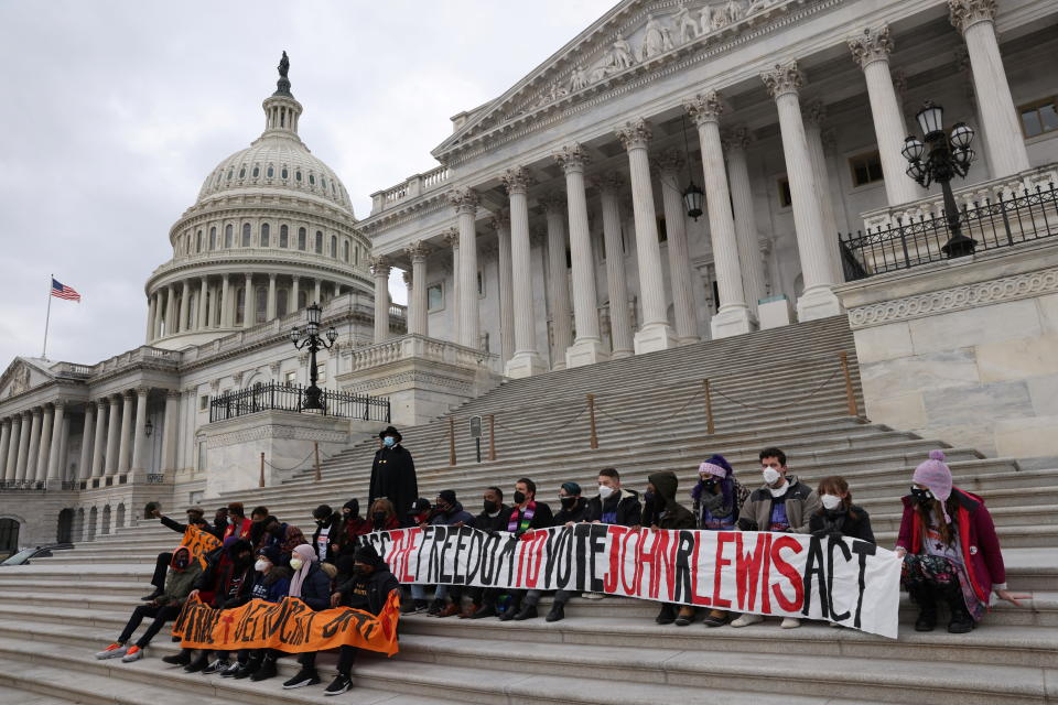 People gather, holding banners, on the steps of the Capitol building.