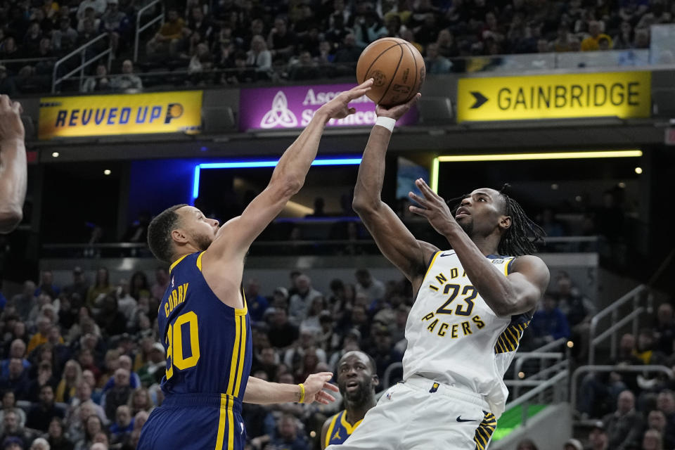 Indiana Pacers' Aaron Nesmith (23) shoots against Golden State Warriors' Stephen Curry (30) during the first half of an NBA basketball game, Thursday, Feb. 8, 2024, in Indianapolis. (AP Photo/Darron Cummings)