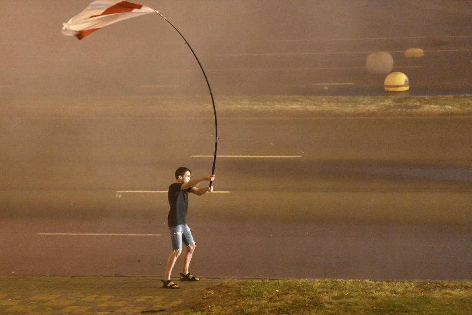 FILE In this Sunday, Aug. 9, 2020 file photo, a protester stands with an old Belarusian national flag as police use a water cannon against demonstrators after the Belarusian presidential election in Minsk, Belarus.President Alexander Lukashenko earned the nickname of “Europe’s last dictator” in the West for his relentless repression of dissent since taking the helm in 1994. was once called “Europe’s last dictator” in the West and has ruled Belarus with an iron fist for 27 years. But when massive protests that began last August presented him with an unprecedented challenge, he responded with exceptional force. (AP Photo, file)