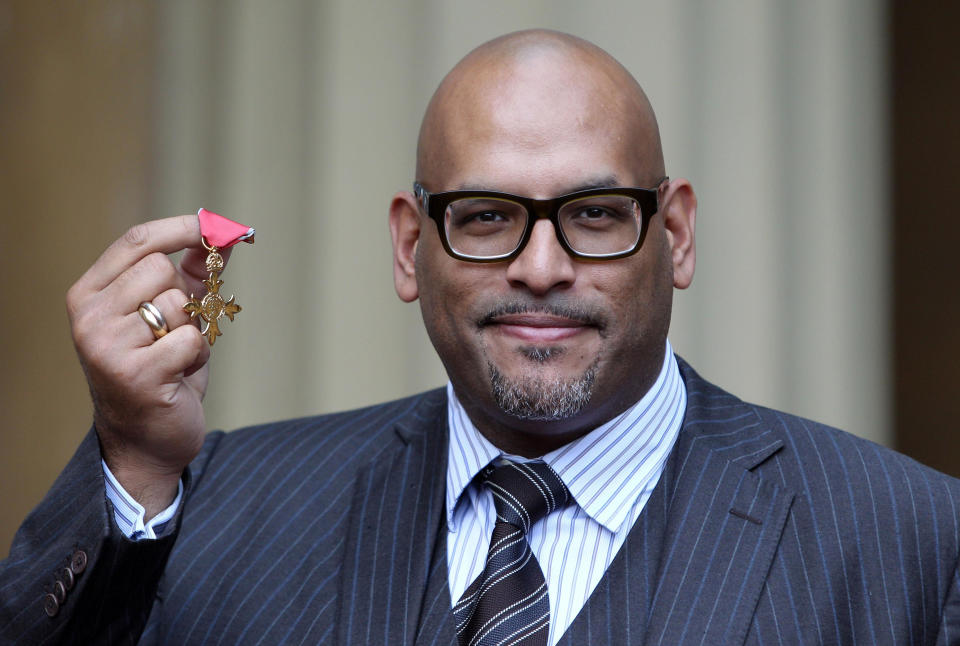 FILE - In this Wednesday Oct. 26, 2011 file photo, Britain's first NBA basketball star John Amaechi holds up his Officer of the British Empire Medal, OBE, from the Prince of Wales at an Investiture ceremony in Buckingham Palace, London. Amaechi, who runs a consulting firm in Britain, has been serving on the diversity board of the London Organizing Committee for the Olympic Games. The committee, known as LOCOG, made diversity and inclusion a cornerstone of its bid to host the games. (AP Photo/Pool, PA, Lewis Whyld)