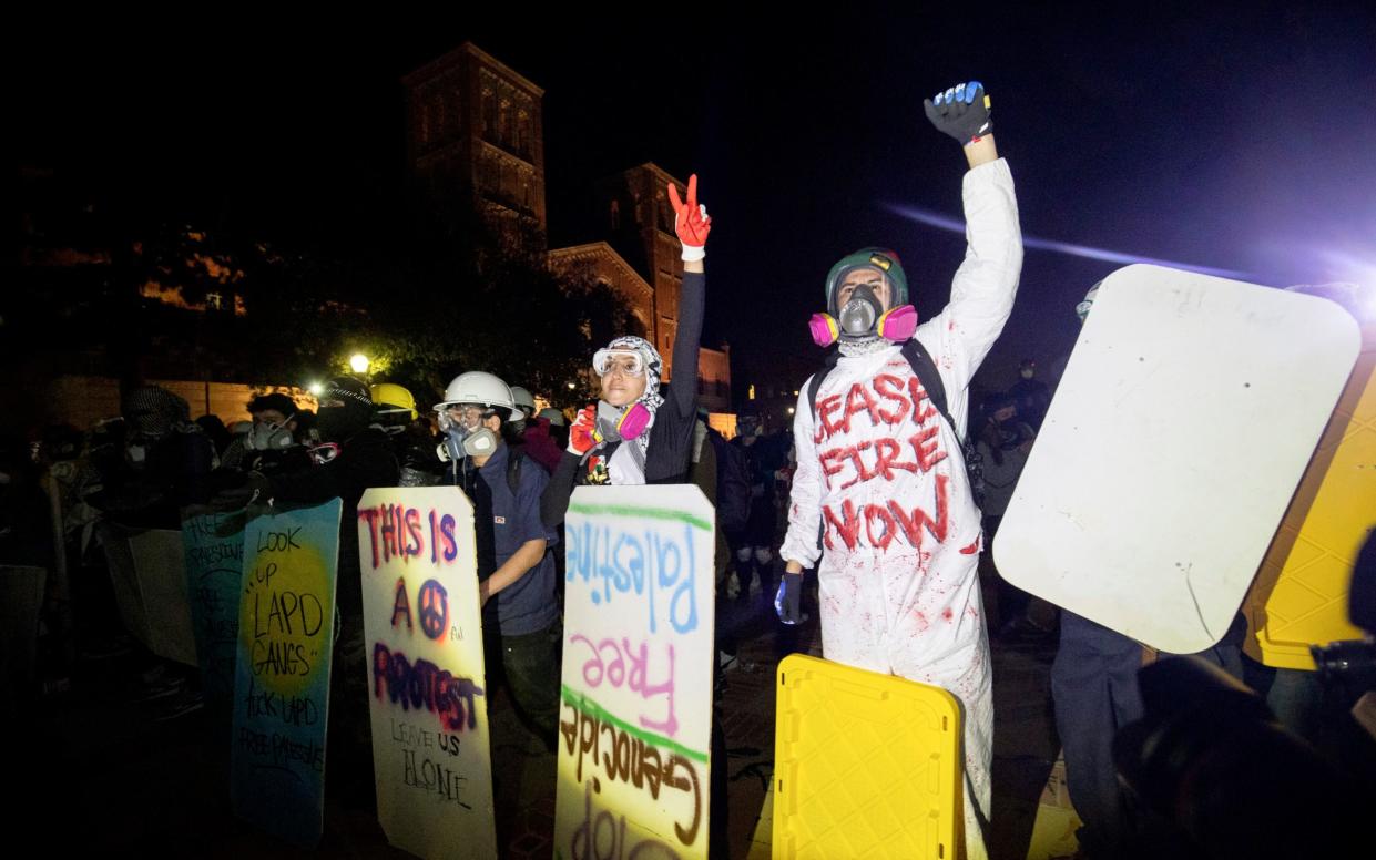 Demonstrators line up behind makeshift shields as police prepare to advance on them on the UCLA campus