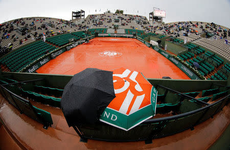 FILE PHOTO: View of the Suzanne Lenglen court as spectators protect themselves from the rain with umbrella before the start of the women's quarter-final match between Svetlana Kuznetsova of Russia and Simona Halep of Romania during the French Open tennis tournament at the Roland Garros stadium in Paris, France, June 4, 2014. REUTERS/Stephane Mahe/File Photo