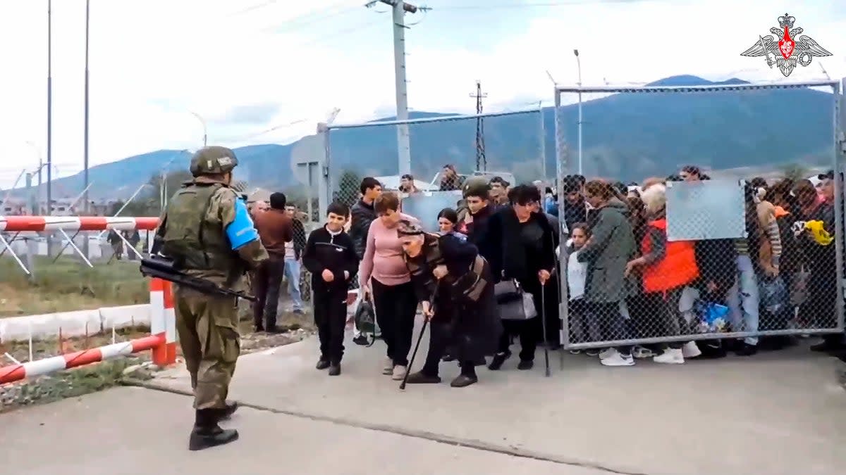 Ethnic Armenians enter a camp near Stepanakert in Nagorno-Karabakh on Thursday as a Russian military peacekeeper looks on (Russian Defense Ministry Press Service)