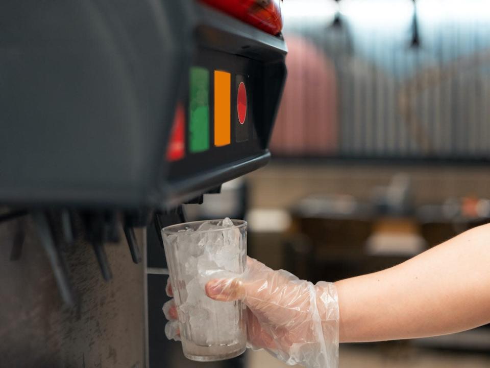 A person fills up a cup with ice.