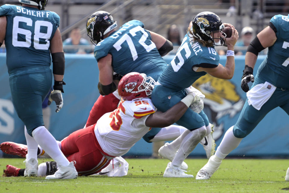 Jacksonville Jaguars quarterback Trevor Lawrence (16) works to escape the grasp of Kansas City Chiefs defensive tackle Chris Jones (95) during the first half of an NFL football game, Sunday, Sept. 17, 2023, in Jacksonville, Fla. (AP Photo/Phelan M. Ebenhack)