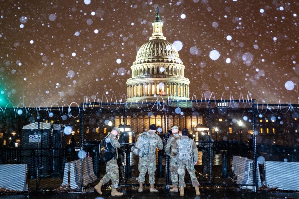 National Guard troops in front of a fence topped with barbed wire outside the Capitol