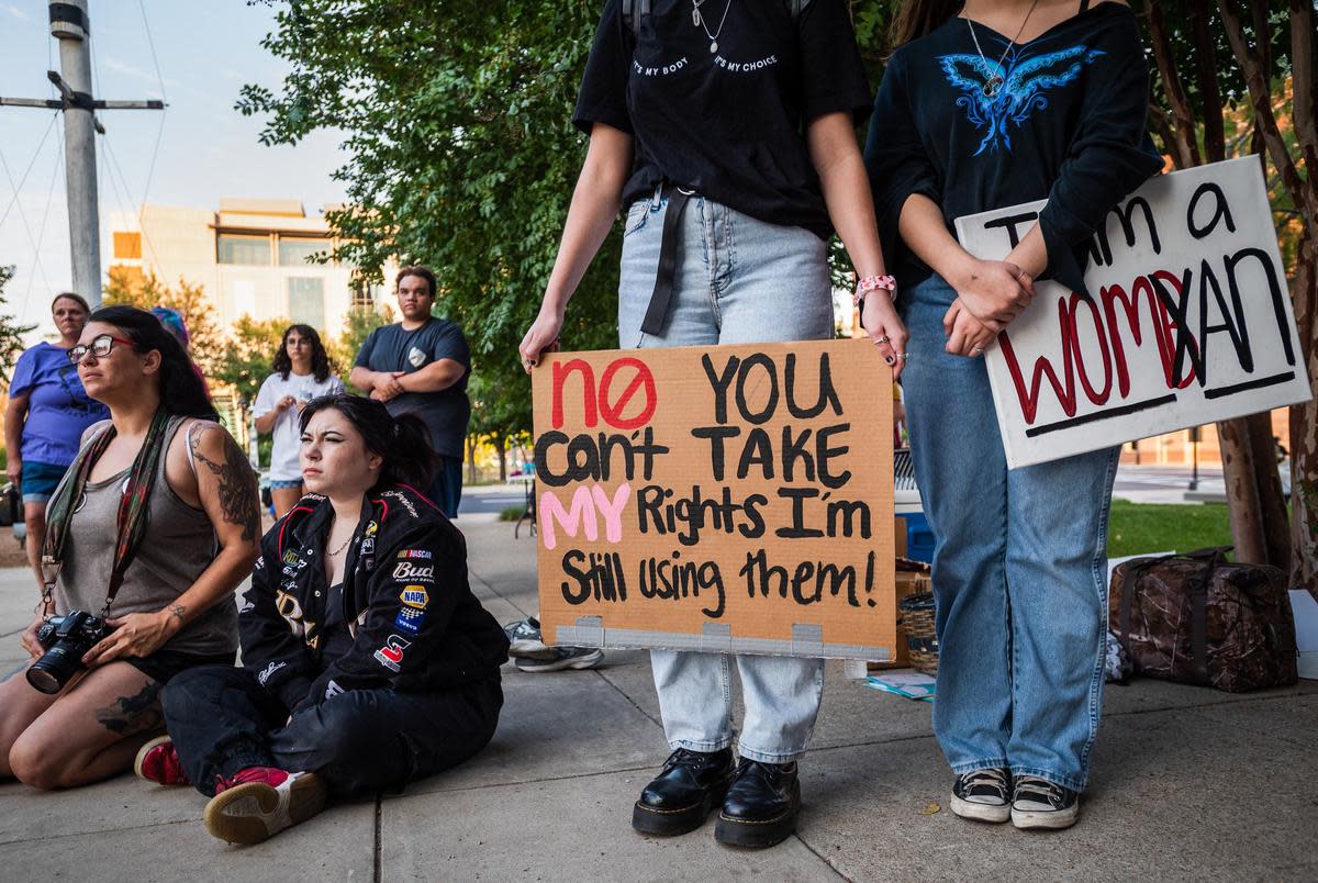 Protestors holding a variety of signs showing support of women's rights, listen to a speaker during a Women's Wave protest, hosted by Bans Off Our Bodies Fort Worth, on Oct. 8, 2022 outside of the Tarrant County Courthouse in downtown Fort Worth.