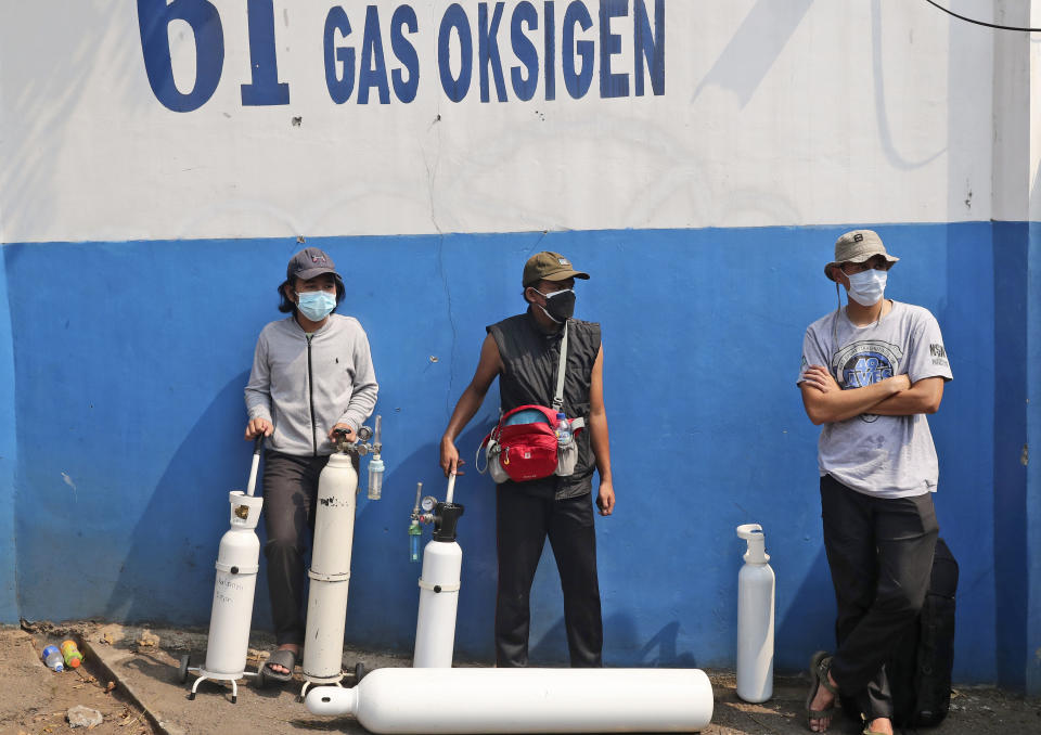 People wait for their turn to refill their oxygen tanks at a recharging station in Jakarta, Indonesia, Friday, July 9, 2021. The world's fourth most populous country is running out of oxygen as it endures a devastating wave of coronavirus cases and the government is seeking emergency supplies from other countries, including Singapore and China. (AP Photo/Tatan Syuflana)