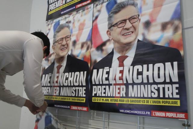 Un partidario del dirigente izquierdista Jean-Luc Melenchon coloca carteles electorales con la leyenda &quot;Melenchon Primer Ministro&quot; en Lille, norte de Francia, 5 de mayo de 2022