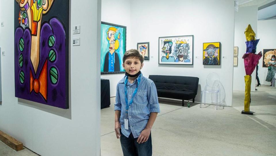 Artist Andres Valencia, 10, stands at his booth in the Art Miami fair during Miami Art Week. The painting in the center is his homage to Jean-Michel Basquiat.