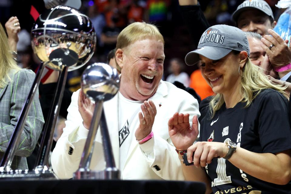 Becky Hammon and Mark Davis pose with the WNBA championship trophy.