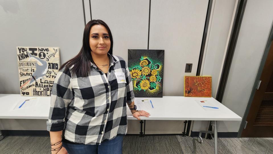 Liz Cuevas stands with her painting Friday night at the HeART of CASA fundraiser in downtown Amarillo.