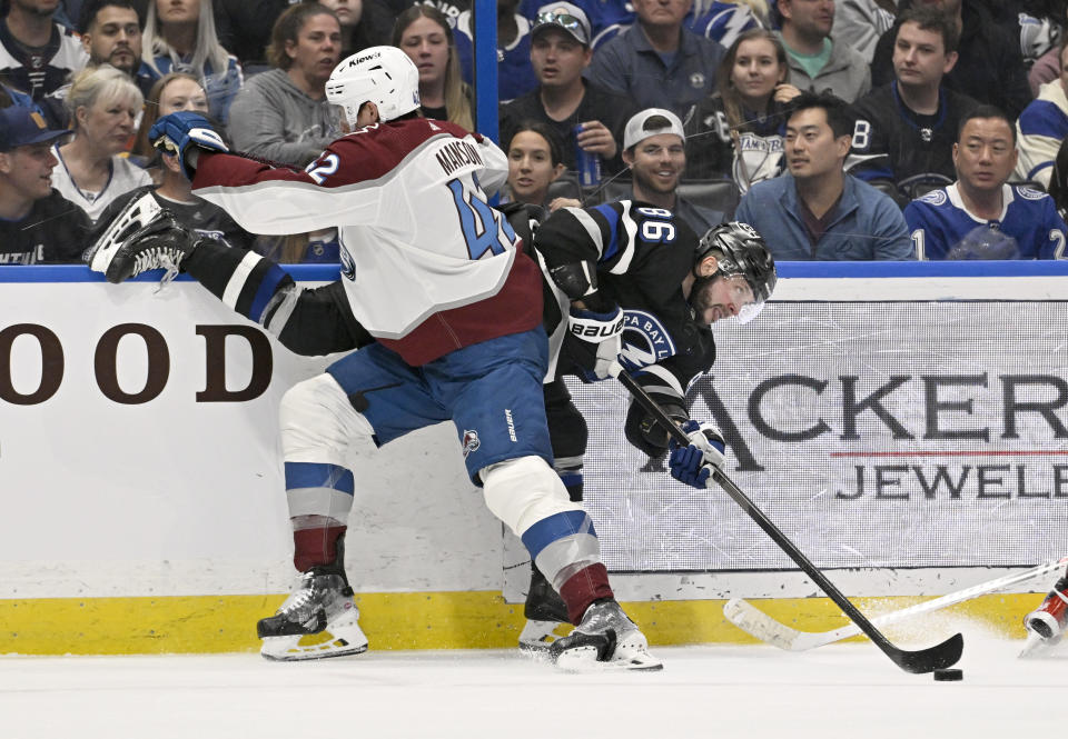 Tampa Bay Lightning right wing Nikita Kucherov (86) plays the puck as he is checked by Colorado Avalanche defenseman Josh Manson (42) during the second period of an NHL hockey game Thursday, Feb. 15, 2024, in Tampa, Fla. (AP Photo/Jason Behnken)