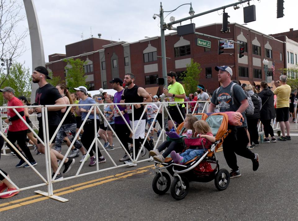 Joe Roof ,of North Canton, with kids Eleanor, 4, and Lydia 2, runs along with his wife, Abby Roof, at the start of her race during Sunday's Canton Hall of Fame Marathon.