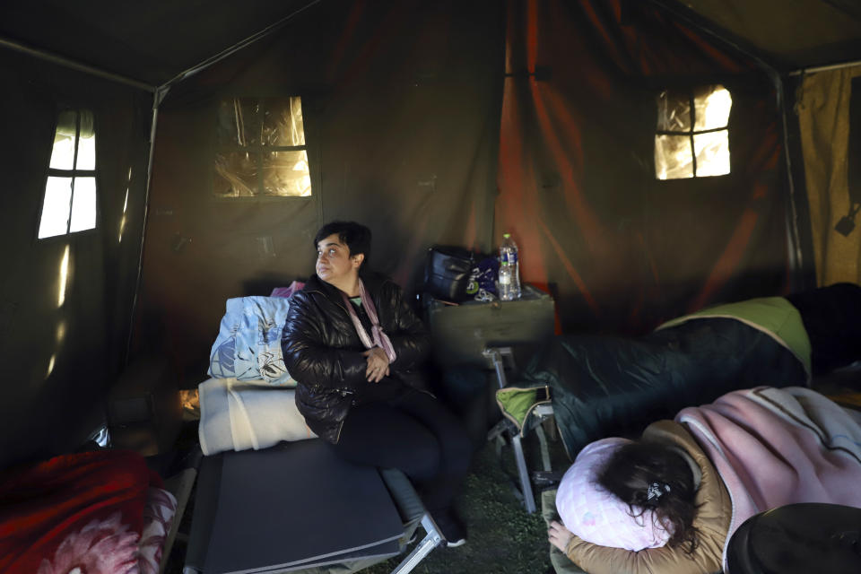 A woman sits inside a tent as others sleep after an earthquake in Damasi village, central Greece, Thursday, March 4, 2021. Fearful of returning to their homes, thousands of people in central Greece spent the night outdoors after a powerful earthquake, felt across the region, damaged homes and public buildings. (AP Photo/Vaggelis Kousioras)