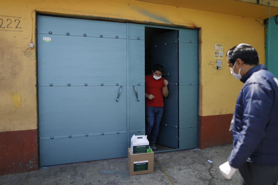 Una persona cuya tía sufre de síntomas similares al COVID-19 recibe paquetes, uno con materiales médicos y otro con alimentos, que le fueron llevados hasta su casa por trabajadores del gobierno en la delegación Coyoacán, en la Ciudad de México, el jueves 9 de abril de 2020. La asistencia también incluye una tarjeta en la que la persona beneficiaria tiene disponible 1.000 pesos (unos 42 dólares). (AP Foto/Rebecca Blackwell)