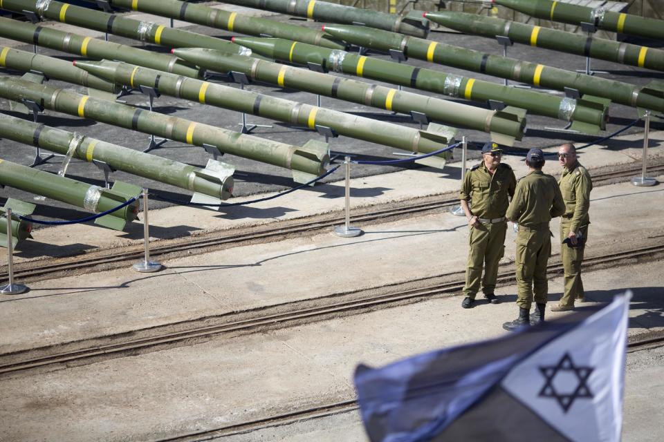 Israeli naval officer stand next to dozens of rockets on display after being seized from the Panama-flagged KLOS C civilian cargo ship that Israel intercepted last Wednesday off the coast of Sudan, at a military port in the Red Sea city of Eilat, southern Israel, Monday, March 10, 2014. Israel has alleged the shipment was orchestrated by Iran and was intended for Islamic militants in Gaza, a claim denied by Iran and the rockets' purported recipients. Questions remain, including how the rockets would have been smuggled into Gaza, largely cut off from the world by a border blockade enforced by Israel and Egypt. (AP Photo/Ariel Schalit)