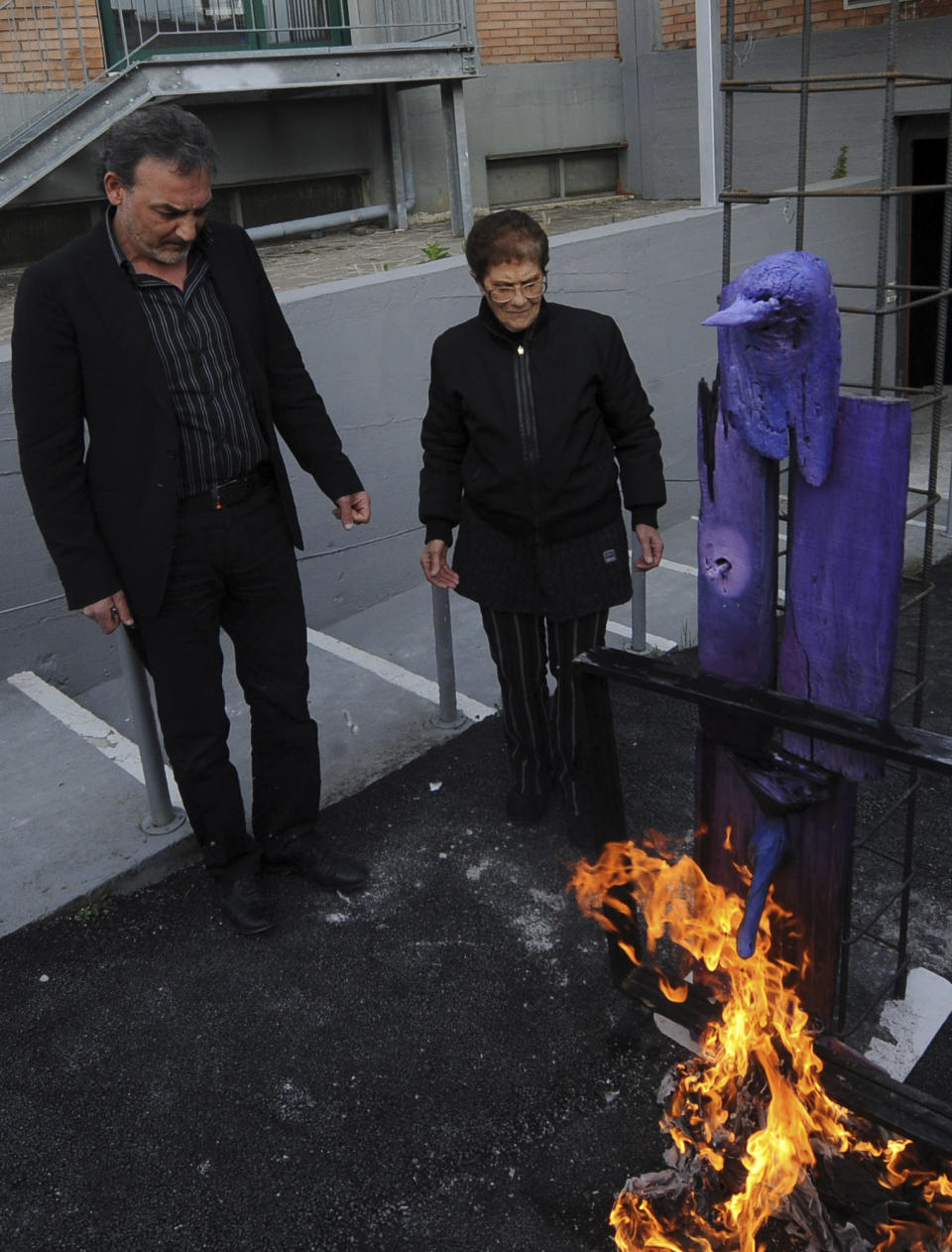 Antonio Manfredi, left, director of the Casoria Contemporary Art Museum, and Italian artist Rosaria Matarese burn one of Matarese's creations in front of the museum, near Naples, Wednesday, April 18, 2012. This is the second creation Manfredi burnt, the day before he burned a painting by a French artist, to protest shortage of funds. Manfredi threatened to burn paintings if financial aid wasn't promised. Italy's museums have been chronically short of funds for decades, but art world officials say the economic crisis has aggravated their pligh. (AP Photo/Franco Castano)