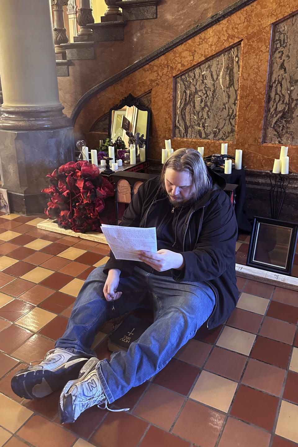 A man recites Christian prayers at a damaged Satanic display at the Iowa state Capitol on Friday, Dec. 15, 2023, in Des Moines, Iowa. The display, which has prompted outrage by some people who say it’s inappropriate at any time but especially during the Christmas holidays, was damaged Thursday. (AP Photo/Scott McFetridge)