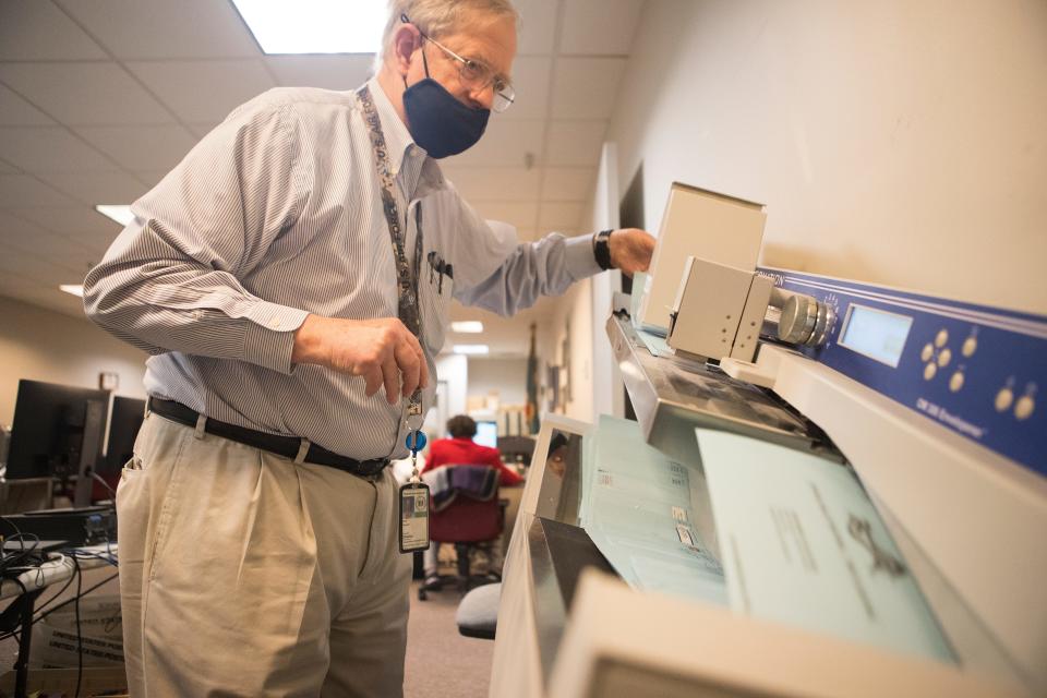 Deputy County Director Howard Sholl feeds mail-in ballots through a machine that will date the ballots as they are received at the Department of Elections New Castle County Office Wednesday, Oct. 14, 2020.