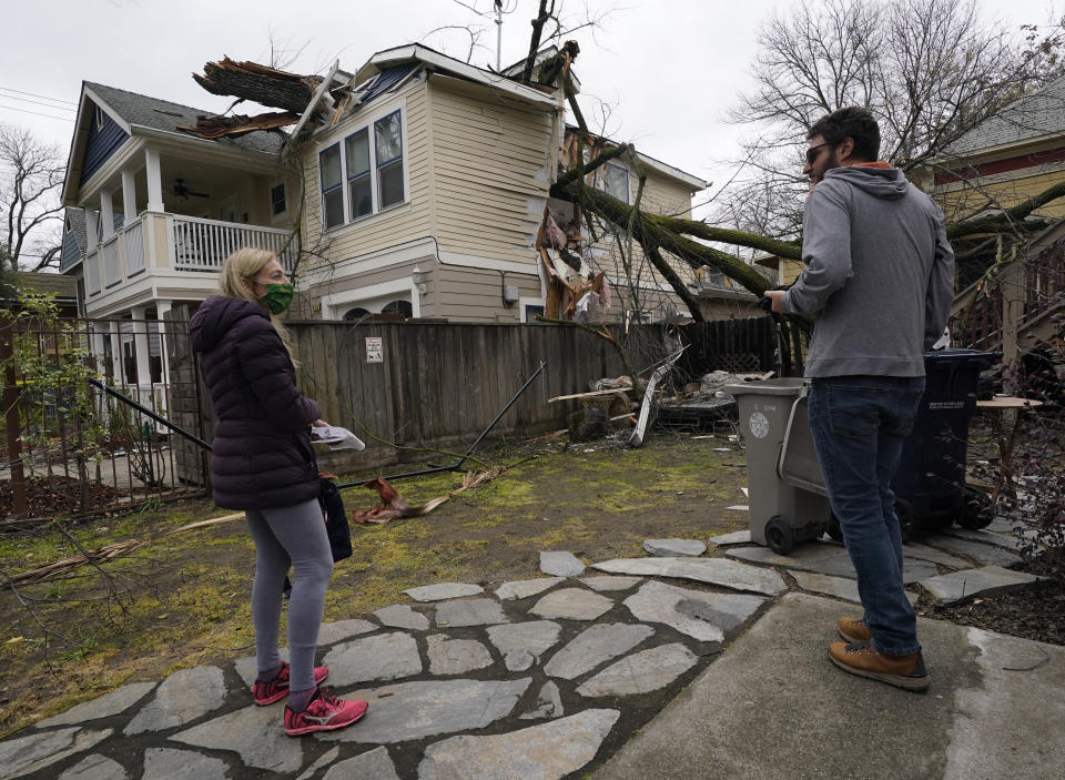 Amy Lilly talks with neighbor Eric Rose as they look over her home damaged by a tree limb that crashed into her house and into Rose's backyard during a storm in Sacramento, Calif., Wednesday, Jan. 27 2021. High-winds and rain pelted the region causing damage throughout the area. (AP Photo/Rich Pedroncelli)