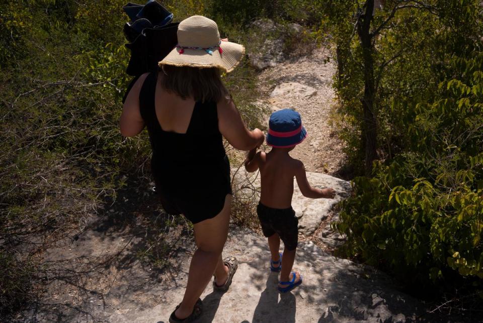 Jailyne Garcia, 20, holds hands with Ezekiel Reyes, 4, while walking toward the creek to swim at McKinney Falls State Park in Austin on July 29, 2023. Garcia and Reyes drove from Houston to spend a day at the state park, a trip they do about three times every summer.