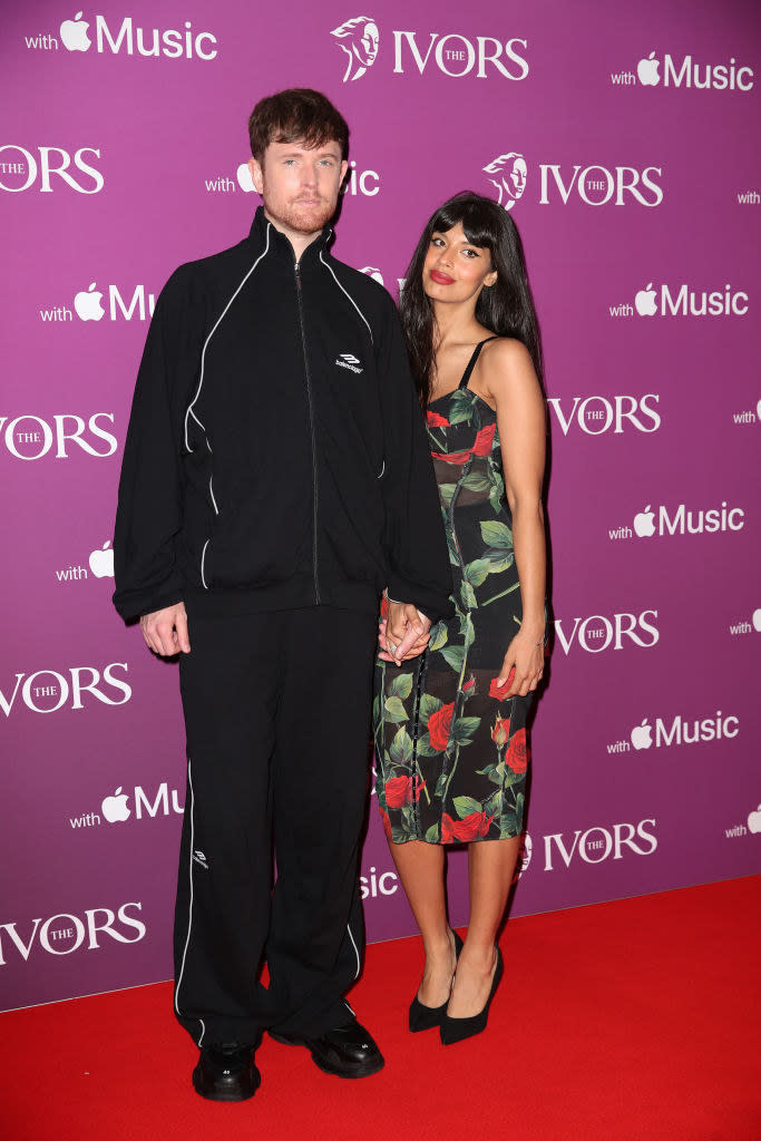 the couple holding hands on the red carpet